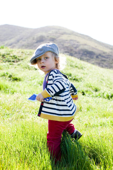 Portrait of male toddler looking back while toddling in grass — Stock Photo