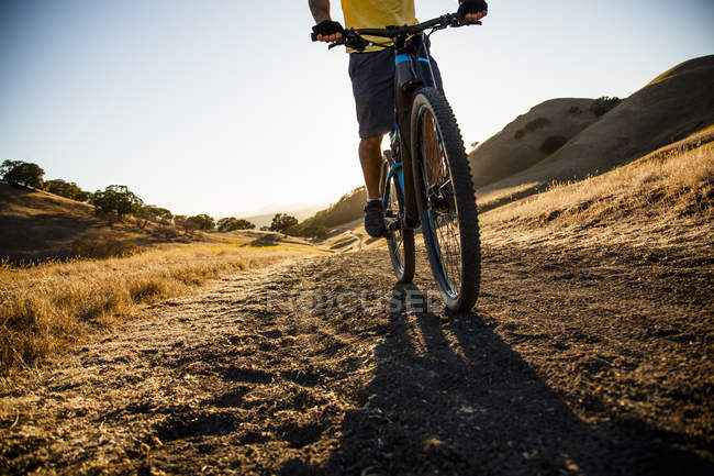 Vista cortada silhueta do jovem ciclismo de montanha para baixo pista de terra, Monte Diablo, Bay Area, Califórnia, EUA — Fotografia de Stock
