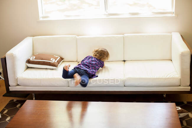 Ragazza che gioca sul divano in soggiorno — Foto stock