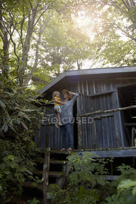 Madre e hija de pie fuera de la cabina de madera - foto de stock
