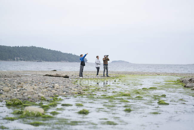 Father and sons taking photographs on beach, Pacific Rim National Park, Vancouver Island, Canada — Stock Photo