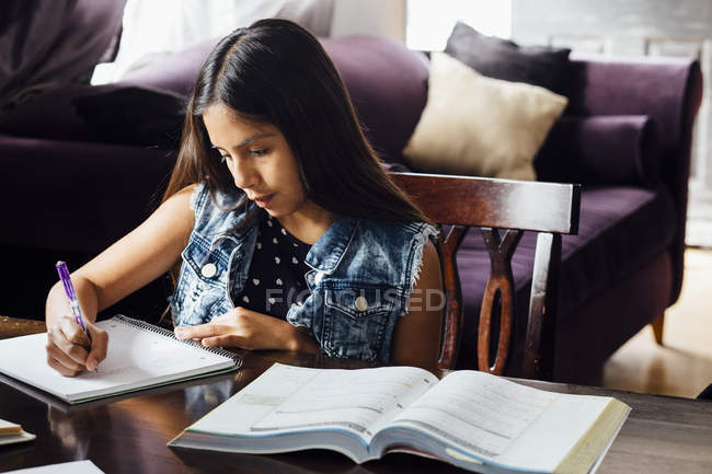 Girl doing homework at table — Stock Photo