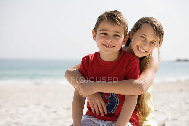 Irmão e irmã abraçando em uma praia — Fotografia de Stock