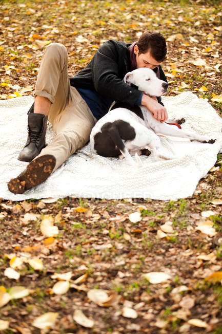Mann und Hund relaxen auf Picknickdecke — Stockfoto