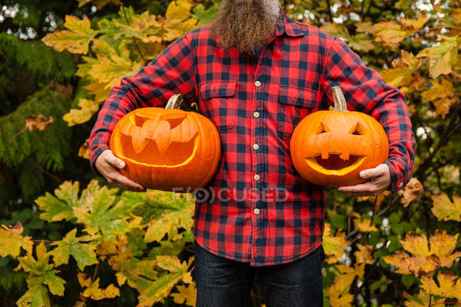 Cropped image of man holding carved pumpkins — Stock Photo