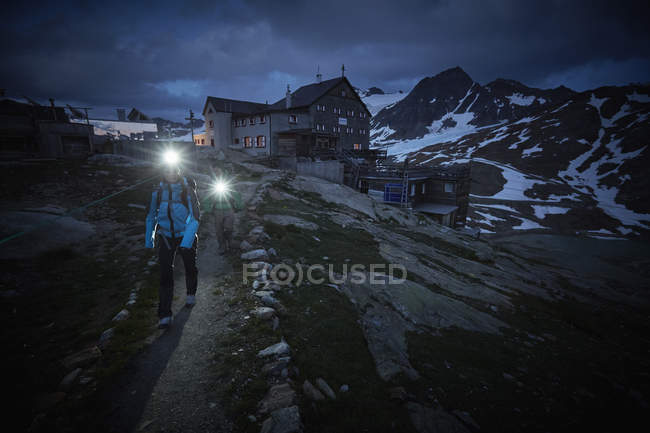 Young couple hiking at night wearing headlamps on path at Val Senales Glacier, Val Senales, South Tyrol, Italy — Stock Photo
