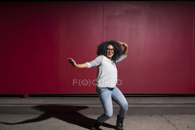Портрет женщины, танцующей перед красной стеной — стоковое фото