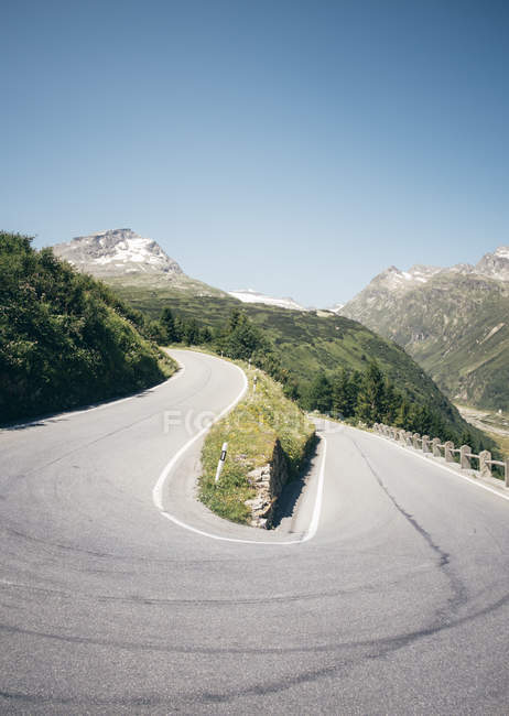 Strada aperta illuminata dal sole che si snoda lungo la montagna — Foto stock