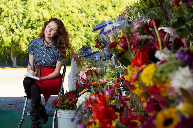 Florist making notes in shop — Stock Photo