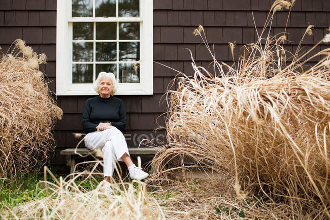 Портрет старшого жінка, сидячи на лавці біля будинку — стокове фото
