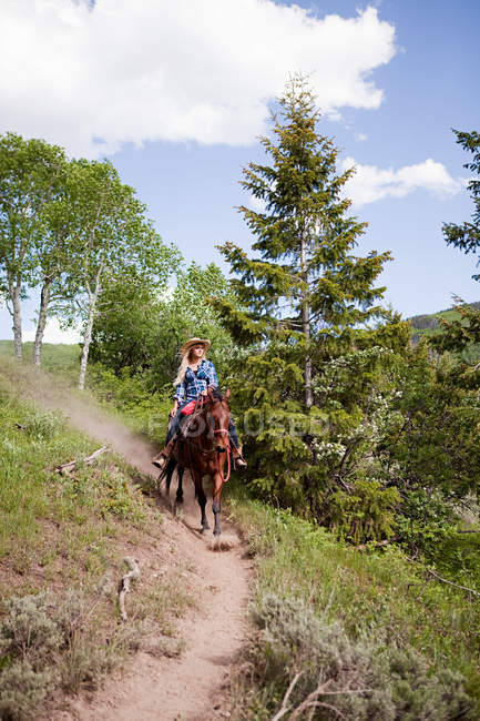 Donna a cavallo attraverso Beaver Creek, Colorado, USA — Foto stock