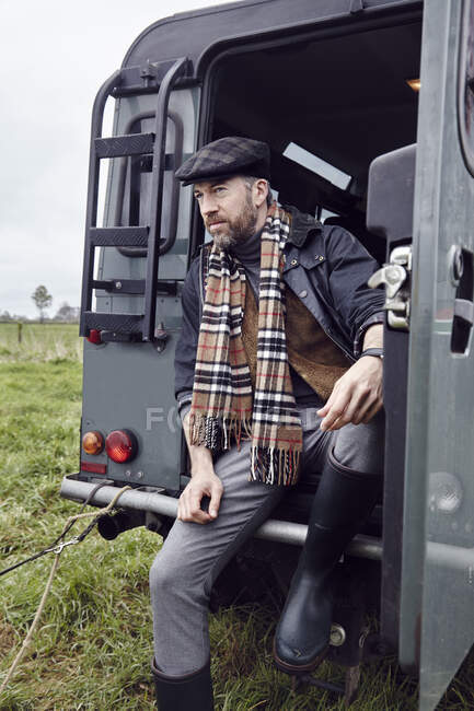 Man in outdoor clothes looking out from back door of off road vehicle — Stock Photo
