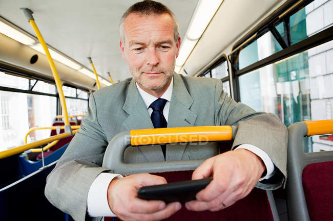 Homme d'affaires utilisant un smartphone sur le bus — Photo de stock