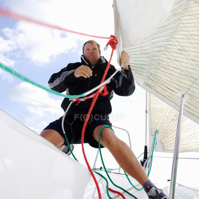 Uomo su yacht, tirando corde — Foto stock