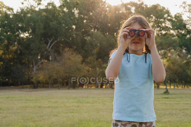 Girl looking through binoculars — Stock Photo