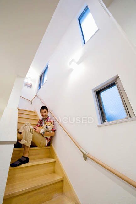 Portrait of young man and dog on wooden staircase — Stock Photo