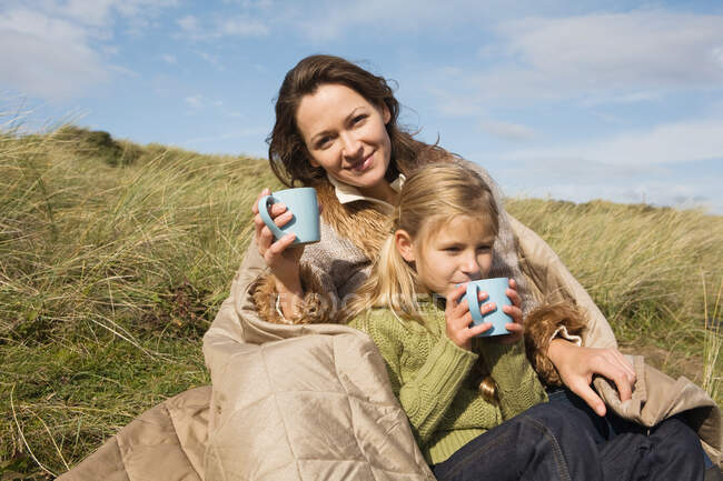 Madre e hija al aire libre con bebidas - foto de stock