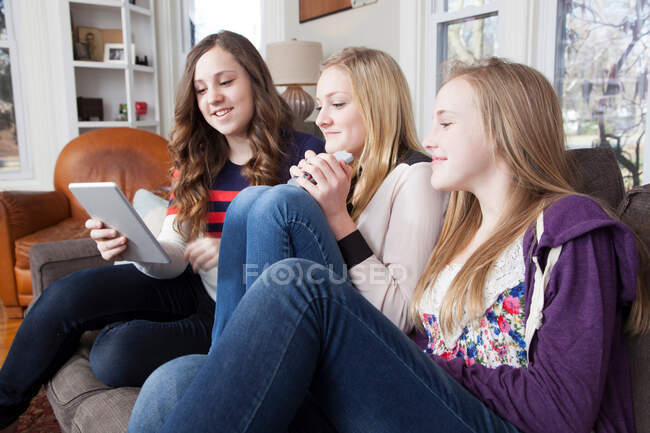 Девушки сидят на диване с помощью цифрового планшета — стоковое фото