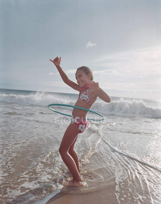 Menina hula hooping em ondas na praia — Fotografia de Stock