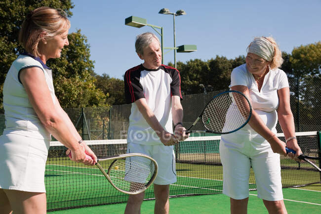 Ältere und ältere Erwachsene üben auf Tennisplätzen — Stockfoto