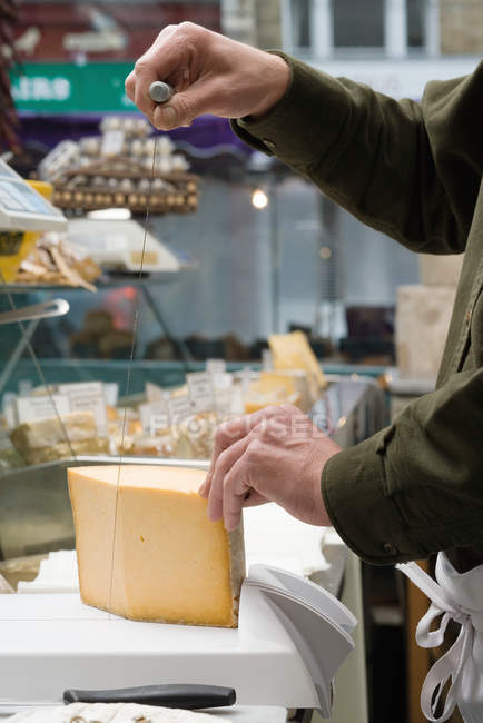 Abgeschnittenes Bild eines Käsehändlers, der Käse schneidet — Stockfoto
