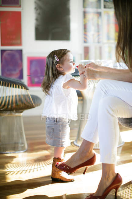 Female toddler trying mother's lipstick — Stock Photo