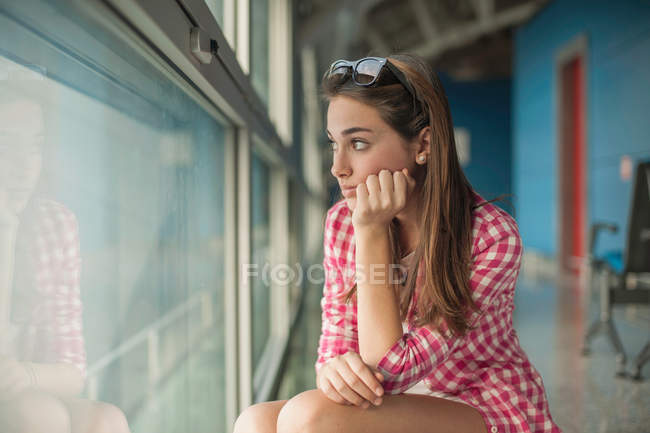 Chica adolescente mirando a través de la ventana - foto de stock