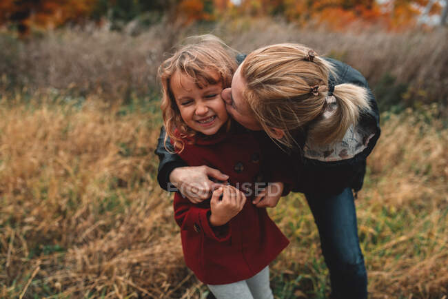 Mulher adulta média beijando filha na bochecha no campo — Fotografia de Stock