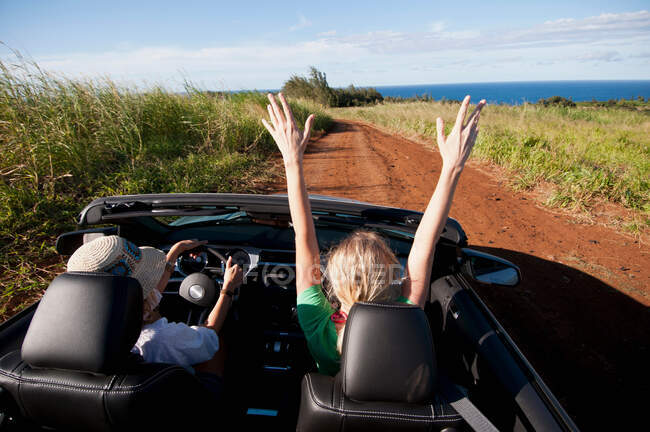 Women driving convertible on dirt road — Stock Photo