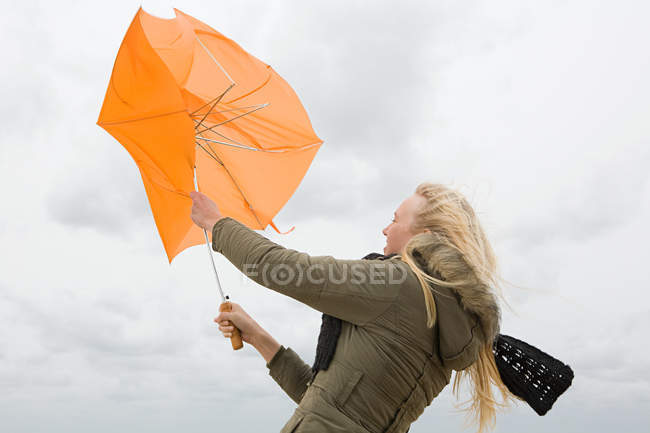 Mujer luchando con paraguas - foto de stock