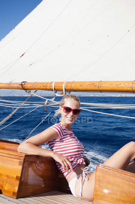 Жінка посміхається сидить на палубі — стокове фото