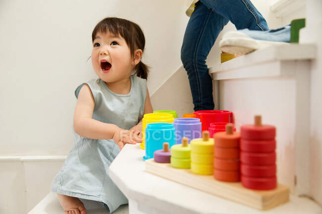 Девочка играет с игрушками на лестничной клетке — стоковое фото