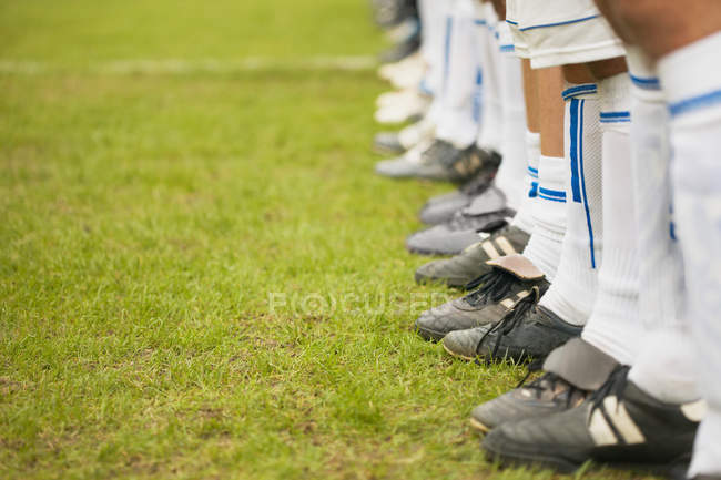 Bassa sezione di giocatori di calcio in fila sullo stadio verde — Foto stock