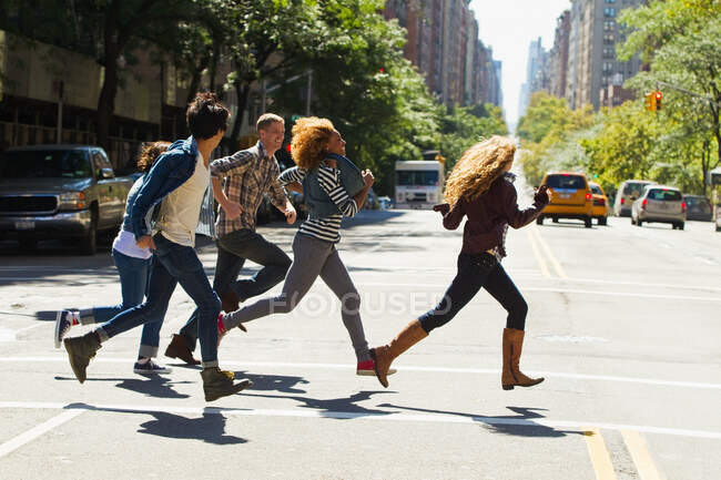 Five friends running through city street — Stock Photo