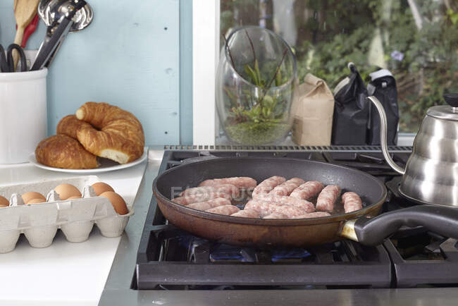 Salsichas de café da manhã fritando na panela na fogão — Fotografia de Stock