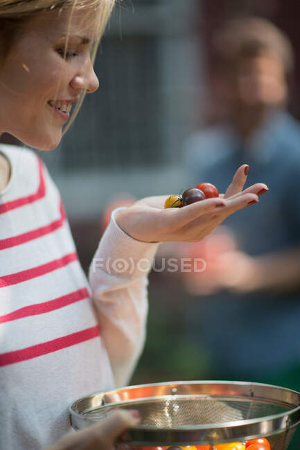 Jeune femme tenant des tomates à la main — Photo de stock