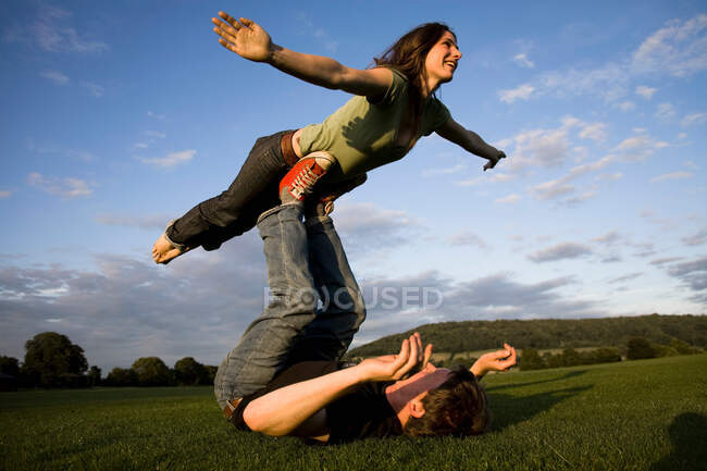 Man balancing girlfriend on his feet — Stock Photo