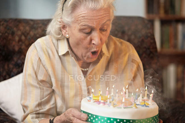 Donna anziana che spegne candele di compleanno — Foto stock
