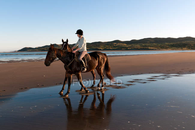 Jovem mulher montando cavalo na praia — Fotografia de Stock