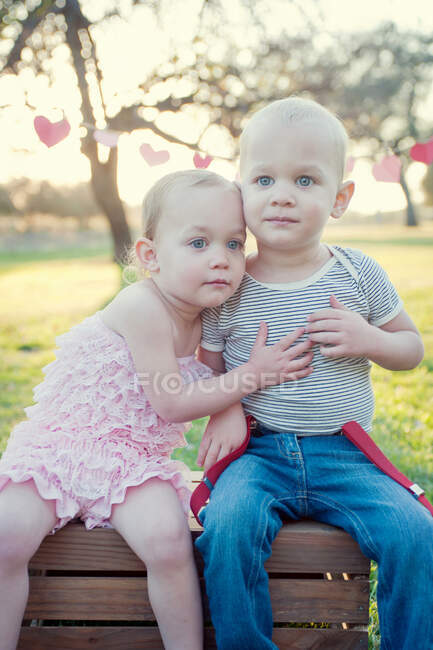 Fratello e sorella seduti all'aperto — Foto stock