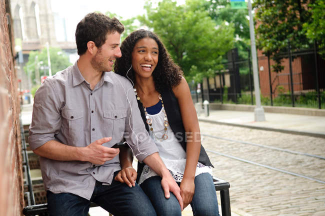 Couple outside building, listening to music on mp3 player — Stock Photo