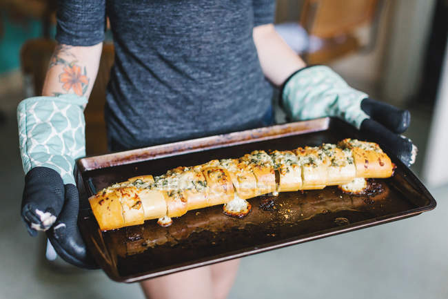 Mid section of young women holding stuffed baguette on baking tin — Stock Photo