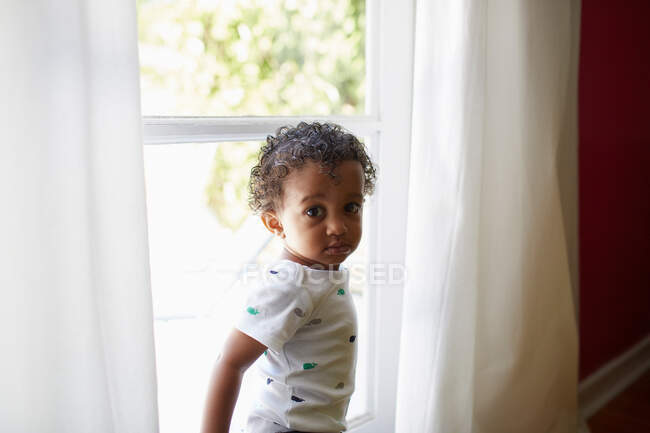 Bambino in piedi accanto alla finestra — Foto stock