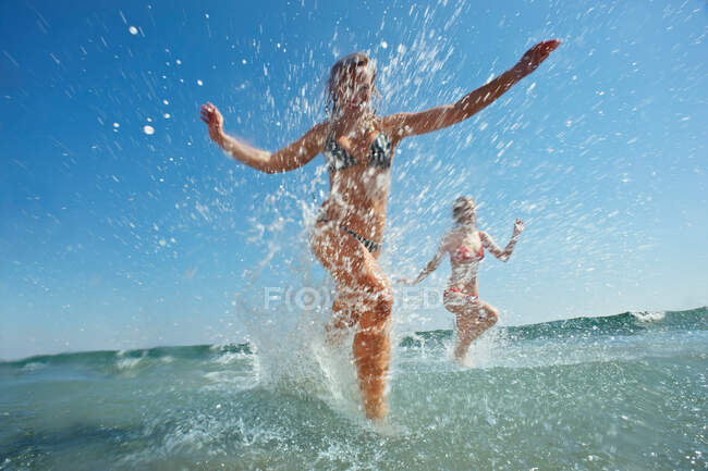 Две девушки, брызгающиеся в море — стоковое фото