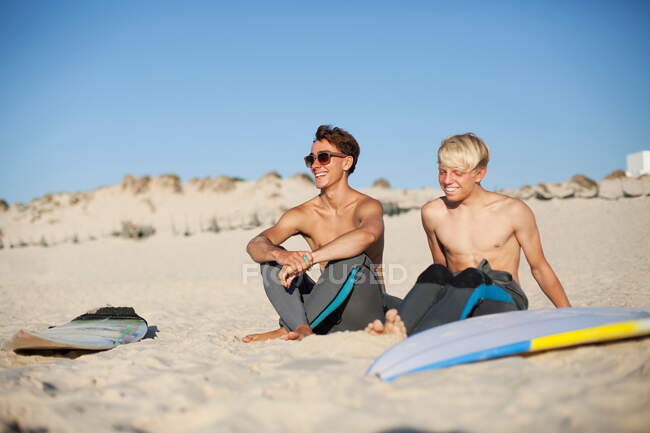 Двоє молодих серферів сидять на пляжі — стокове фото