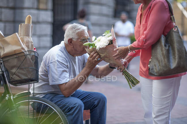 Cape Town, South Africa, elderly man smelling a bunch of flowers — Stock Photo