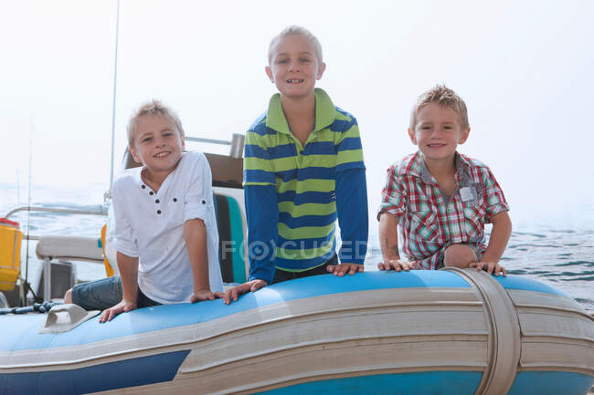 Portrait of three young boys at sea in dinghy — Stock Photo