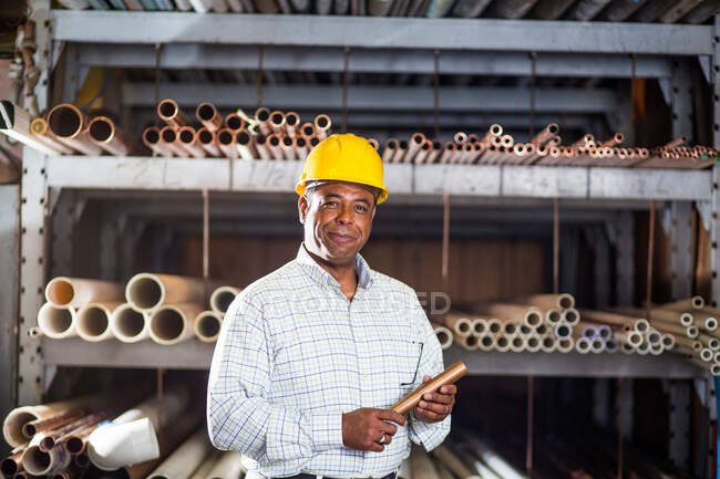Homme en entrepôt avec tuyau en cuivre — Photo de stock