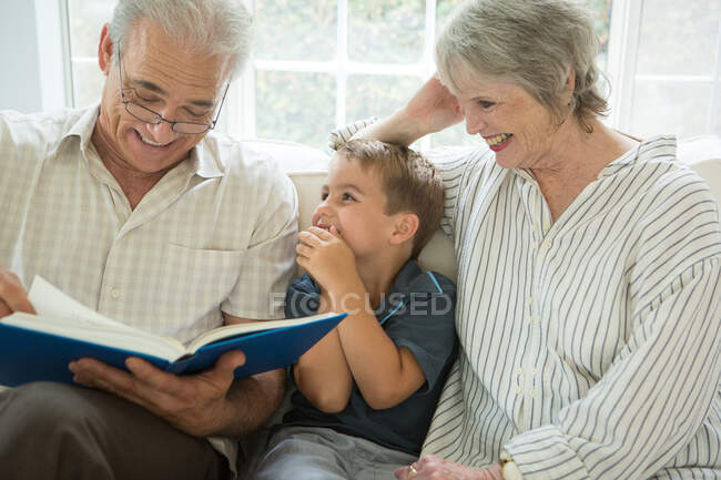 Grandparents showing boy photo album on sofa — Stock Photo