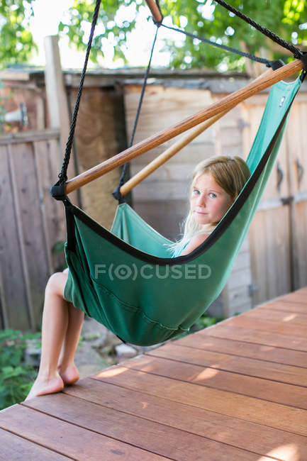 Porträt eines Mädchens, das vom Veranda-Schaukelstuhl über ihre Schulter schaut — Stockfoto